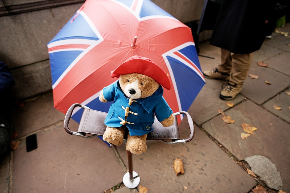 Ein Paddington-Bär sitzt auf einem Stuhl neben einem Schirm mit der britischen Fahne Union Jack, während die Queen beerdigt wurde.