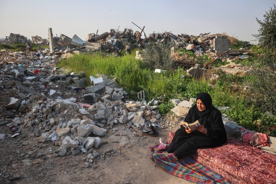 A displaced Palestinian woman reads the Koran before the iftar fast-breaking meal during the Muslim holy month of Ramadan, near building rubble at the Bureij refugee camp in the central Gaza Strip on Wednesday.