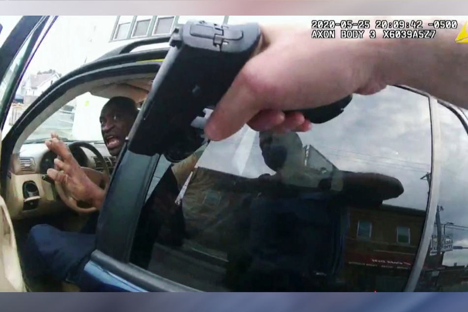 Das Standbild einer Aufnahme von der Körperkamera eines Polizisten zeigt, wie George Floyd (l) am 25. Mai 2020 vor einem Restaurant in seinem Auto sitzt, und eine Waffe auf ihn gerichtet ist.
