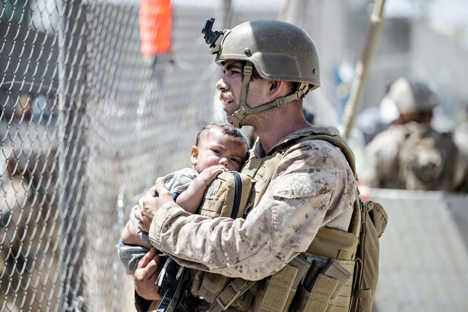A US Marine holds an infant waiting for evacuation outside Kabul airport.