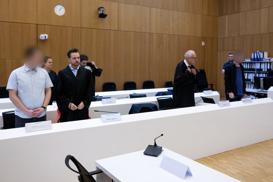 Die Angeklagten (ganz links und ganz rechts) stehen mit ihren Anwälten vor dem Landgericht in München.