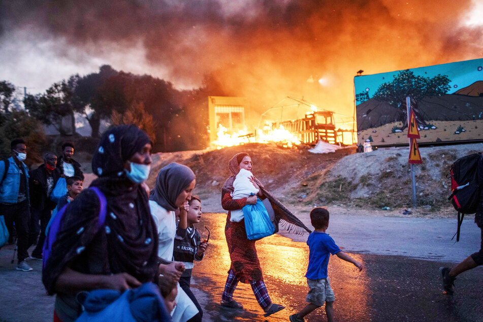 Migranten fliehen vor einem Feuer mit ihren Habseligkeiten aus dem Flüchtlingslager Moria.