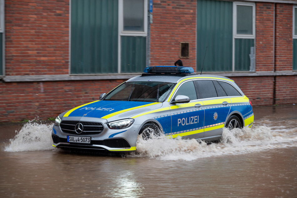 Ein Polizeifahrzeug fährt durch die überflutete Fischbachstrasse in Saarbrücken.