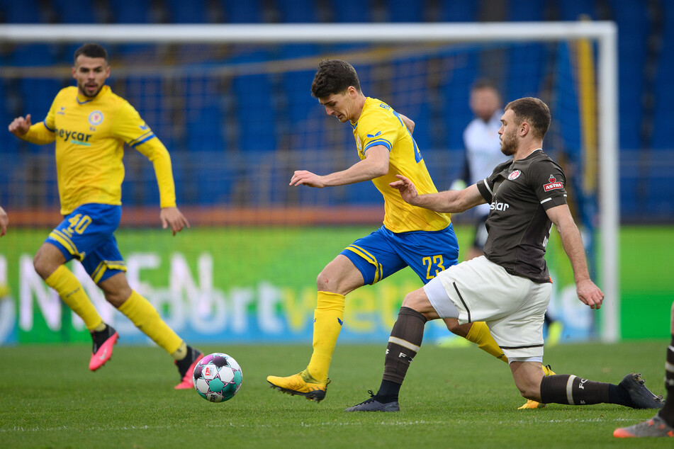 Braunschweigs Danilo Wiebe (m.) spielt gegen St. Paulis Maximilian Dittgen (r.), dahinter läuft Braunschweigs Robin Ziegele.