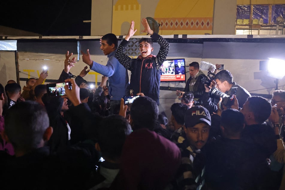 People celebrate while watching a television along a street in Khan Yunis in the southern Gaza Strip on Wednesday, amid the ongoing war in the Palestinian territory between Israel and Hamas.