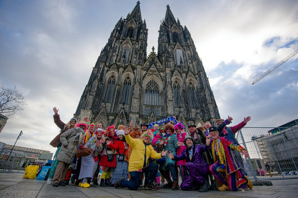 Eine Gruppe von Karnevalisten aus den Niederlanden posiert vor dem Dom für ein Foto.