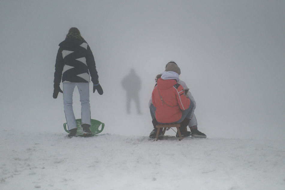 Besucher rodeln im dichten Nebel an einem Abhang (Symbolfoto).