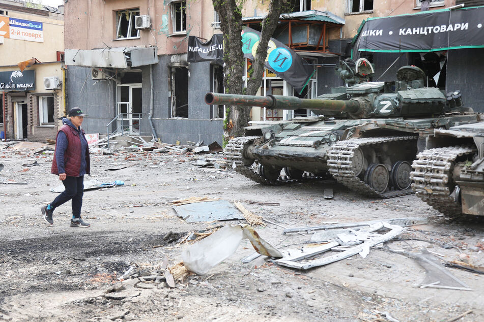 Eine Frau geht an Panzern der Miliz der Donezker Volksrepublik in Mariupol vorbei. Tausende sind dort wohl gestorben.