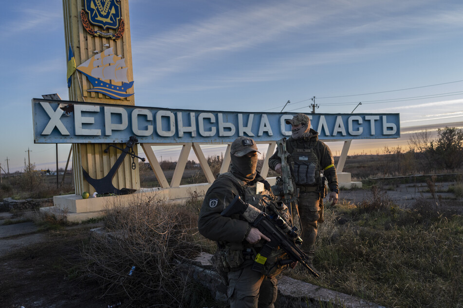 Zwei Mitglieder der ukrainischen Verteidigungskräfte stehen neben einem Schild mit der Aufschrift "Region Cherson". Der Ort wurde vor Kurzem von den Russen zurückerobert.