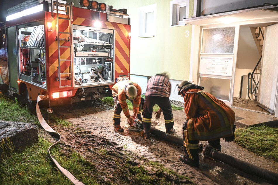 Feuerwehrleute verlegen einen Schlauch, um einen Keller auszupumpen, der beim Hochwasser vollgelaufen ist. Wissenschaftler befürworten schnelle Hilfen nicht unbedingt. (Symbolbild)