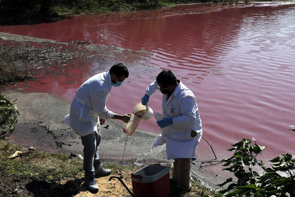 Marcelo Coronel (l.) und Francisco Ferreira, Techniker der Nationalen Universität, nehmen Wasserproben aus der rötlich gefärbten Lagune Cerro, an deren Ufer die Gerberei Waltrading sitzt.