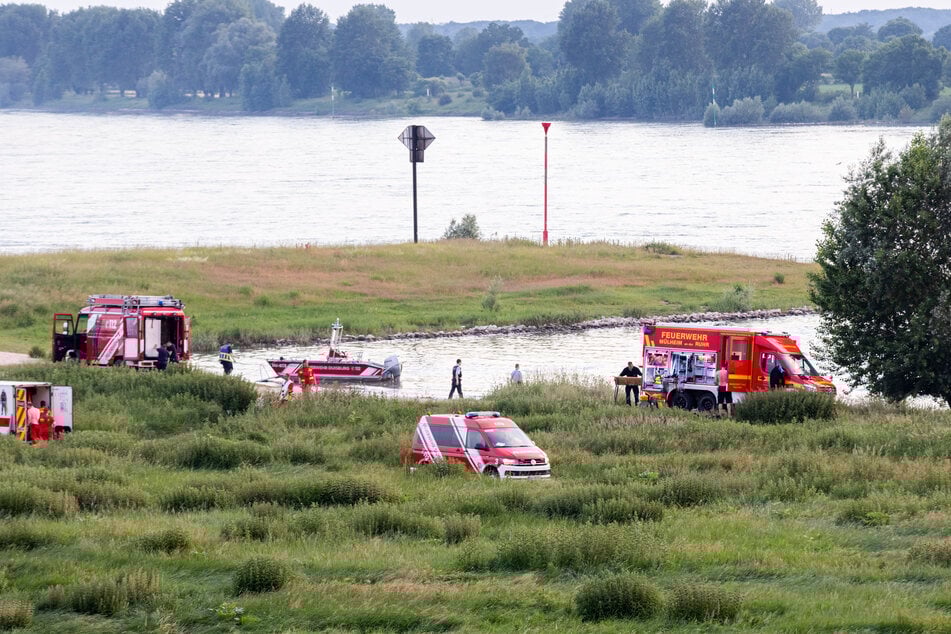 Einsatzkräfte der Polizei, Feuerwehr und DLRG am Ufer des Rheins.