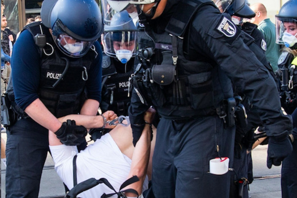 Polizisten führen bei einer Demonstration auf dem Berliner Alexanderplatz einen Mann ab.