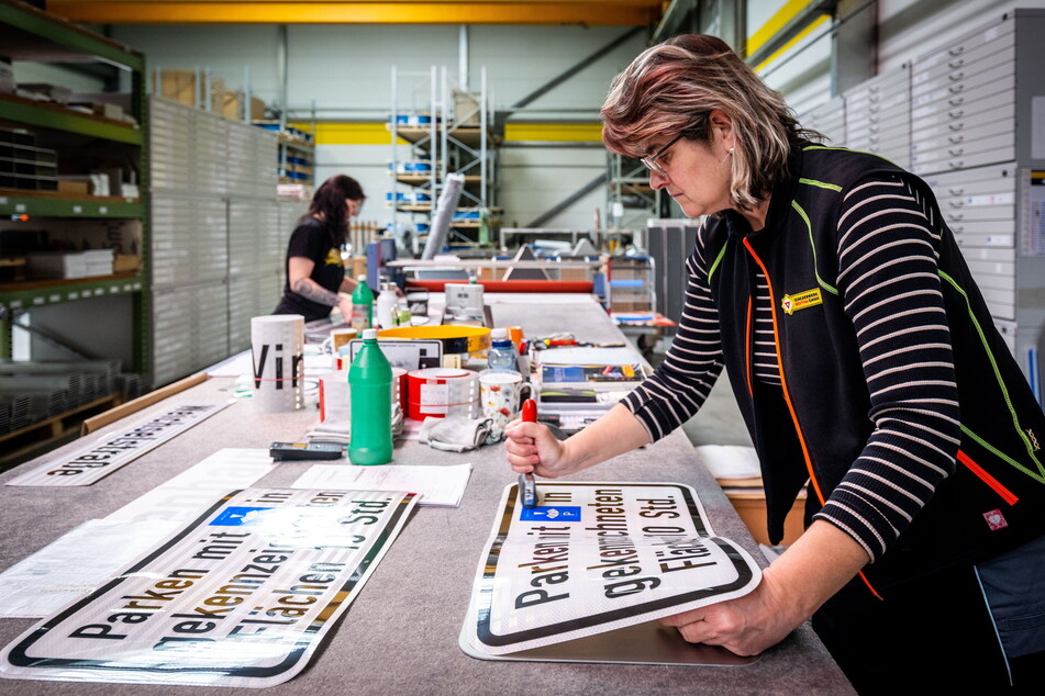 Schilder in kleiner Stückzahl entstehen in Handarbeit: Kathrin Lenk (56) klebt bedruckte Folien auf Aluminiumtafeln.