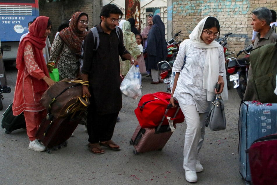 Pakistani students walk with their belongings in Quetta after they returned from Iran following the Israeli strikes, on June 17, 2025.