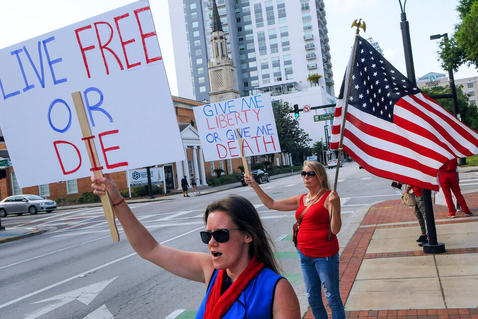 Demonstranten halten Schilder mit den Aufschriften "Live Free or Die" (Lebe frei oder strib) und "Give me liberty or give me Death" (Gib mir Freiheit oder gib mir den Tod) bei einem Proteste gegen die Ausgangsbeschränkungen aufgrund des neuartigen Coronavirus. (Archivbild)