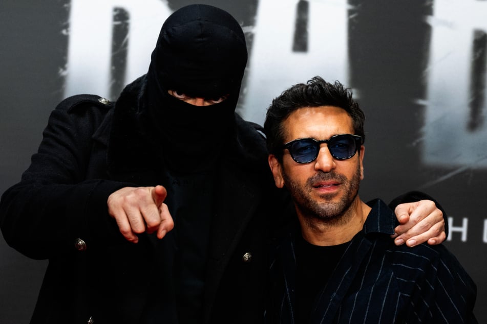 Haftbefehl mit Maske und Schauspieler Elyas M'Barek (43) bei einer Sondervorführung der Netflix-Doku über den Rapper in Berlin, die M'Barek unter anderem produzierte.