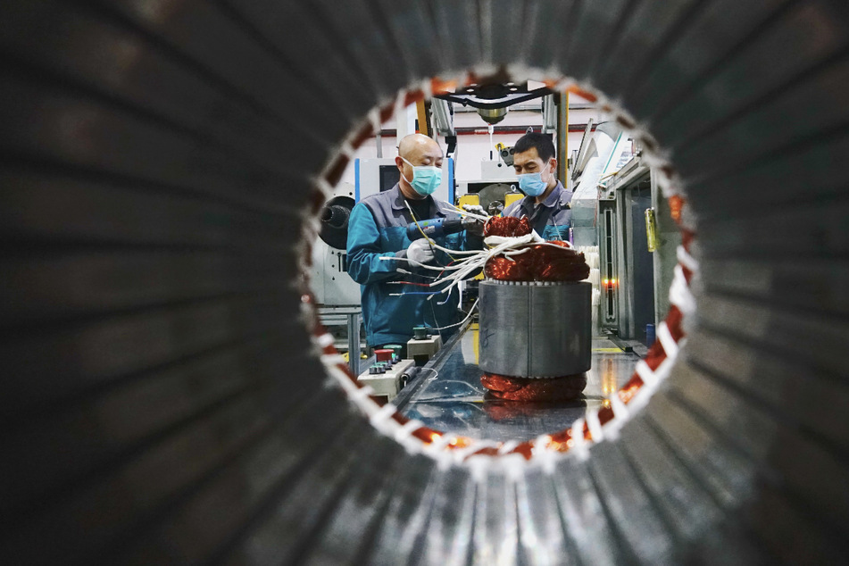 Mitarbeiter mit Mundschutz arbeiten in einem Werk eines Unternehmens im März 2020, das mechanische und elektronische Produkte herstellt, in der "Qinhuangdao Economic and Technological Development Zone" in Qinhuangdao in der Nordchinesischen Provinz Hebei.