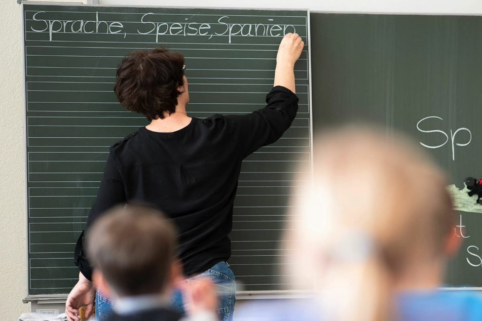 Eine Lehrerin schreibt in einer Grundschule Worte an eine Tafel. Schüler der Klassenstufen 1 bis 3 werden in Berlin bereits seit dem 22. Februar wieder wechselweise unterrichtet. (Symbolfoto)