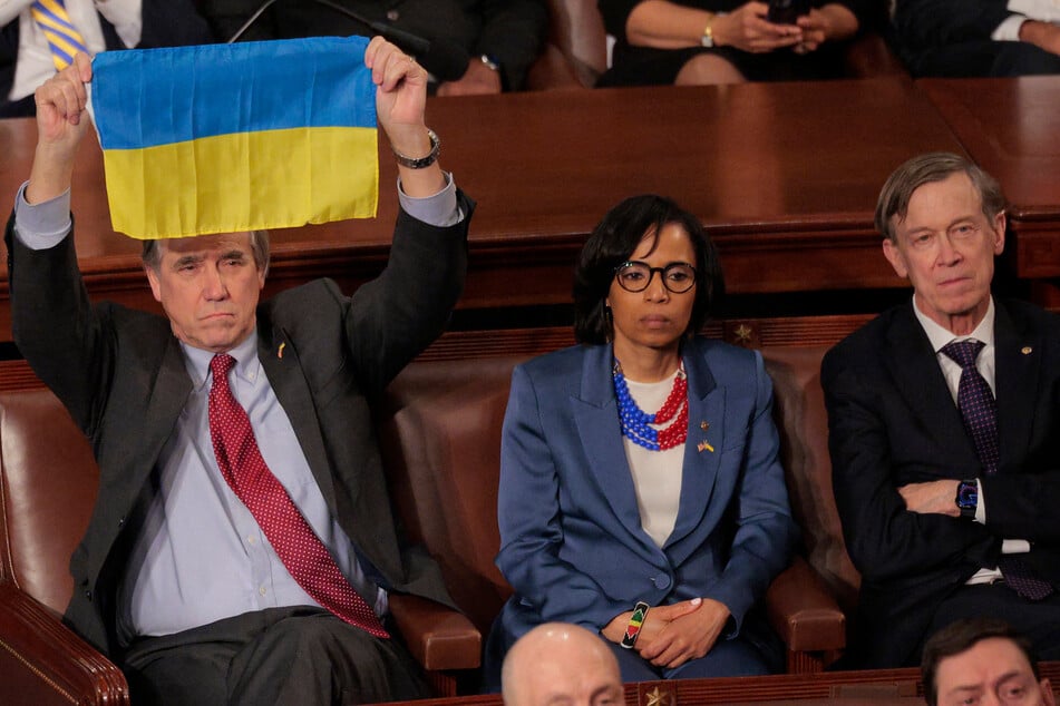 Sen. Jeff Merkley (l.) held up a Ukraine flag during Trump's address.