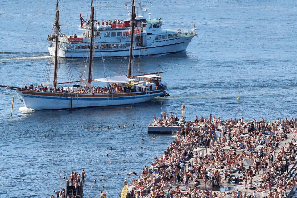 Norwegen, Oslo: Zwei Kreuzfahrtschiffe fahren vor dem vielbesuchten Badebereich Sorenga in der Nähe der Docks entlang.