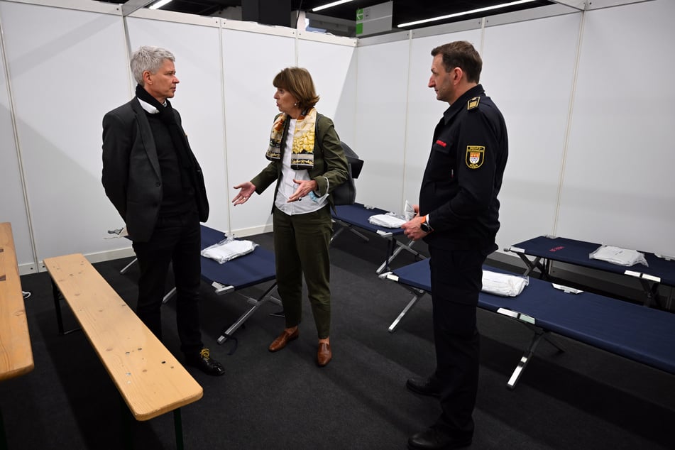 Harald Rau (59) steht links neben Henriette Reker (68), Oberbürgermeisterin der Stadt Köln, und Christian Miller, Chef der Berufsfeuerwehr, in einem Schlafsaal für ukrainische Flüchtlinge. (Archivfoto)