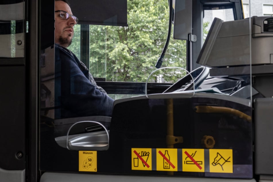 Ein Busfahrer sitzt in seinem BVG-Bus hinter einer neuartigen Sicherheitsverglasung aus Plastik.