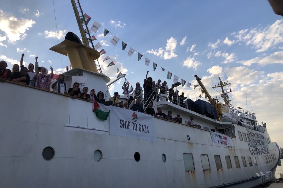 International journalists and medical professionals wave as the Conscience sets sail for Gaza.