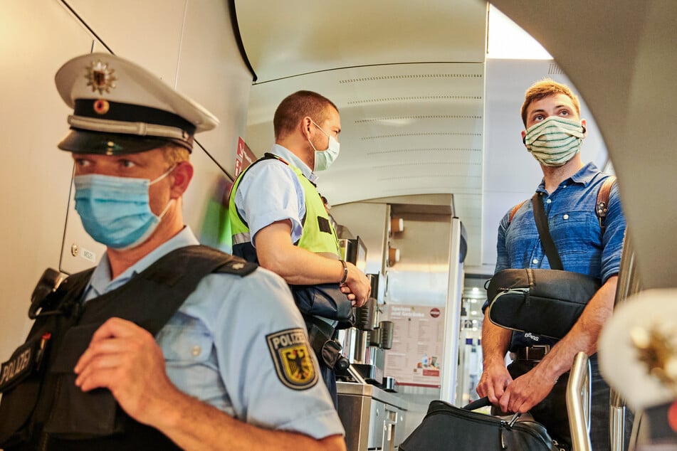 Beamte der Bundespolizei und Mitarbeiter der DB Sicherheit stehen in einem Zug und kontrollieren, ob die Corona-bedingte Maskenpflicht eingehalten wird.