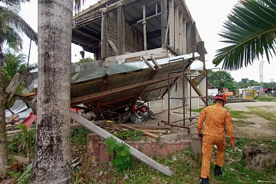 Ein Feuerwehrmann geht an einem beschädigten Gebäude vorbei, das durch ein starkes Erdbeben in der Provinz Davao Oriental im Süden der Philippinen beschädigt wurde.