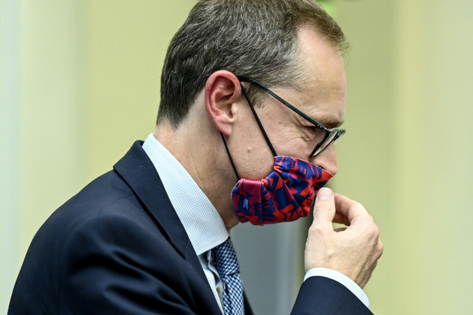 Michael Müller (SPD) setzt sich am Rande der Senats-Pressekonfernz über neue Maßnahmen zur Eindämmung der Corona-Pandemie den Mund-Nasen-Schutz auf.