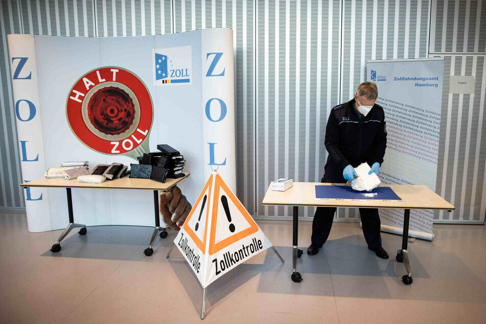 Ein Zollbeamter präsentiert gepresstes und hoch konzentriertes Kokain aus einem großen Kokainfund im Rahmen einer Pressekonferenz des Zoll Hamburg.
