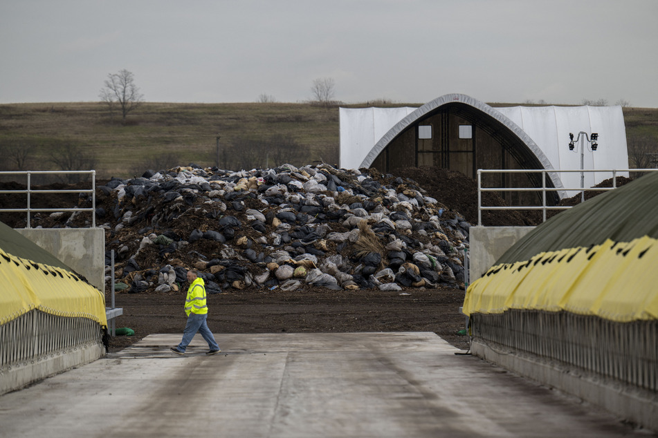 A worker walks past piles of collected leaves at the New York City Department of Sanitation (DSNY) Staten Island Compost Facility on January 4, 2024 in New York City.
