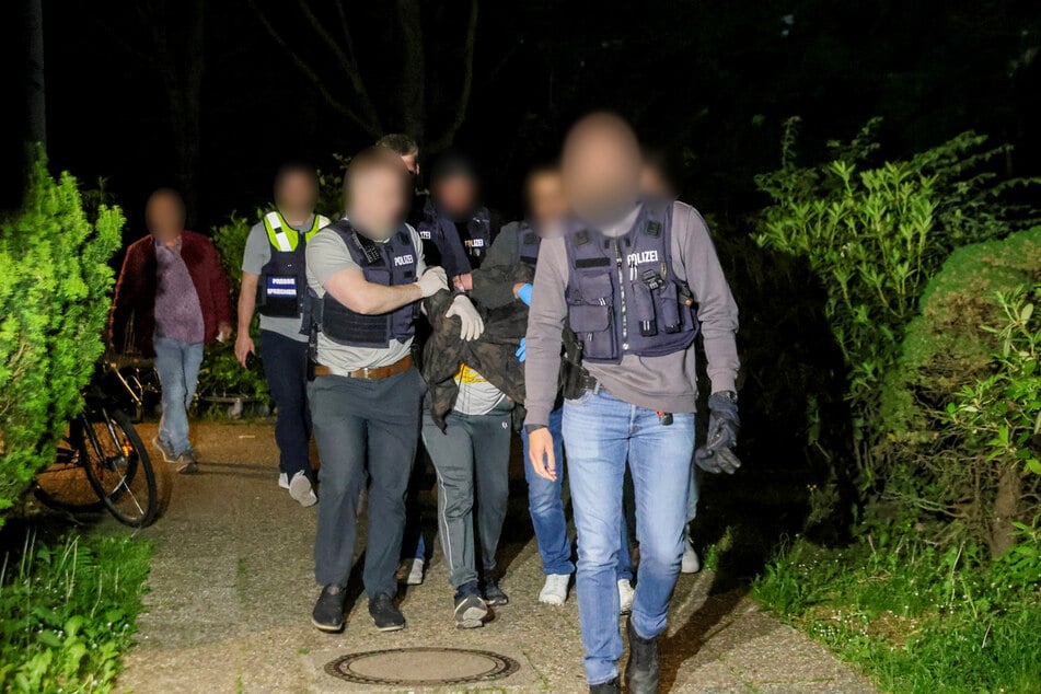 Einsatzkräfte der Polizei führen einen Tatverdächtigen nach seiner Festnahme ab.