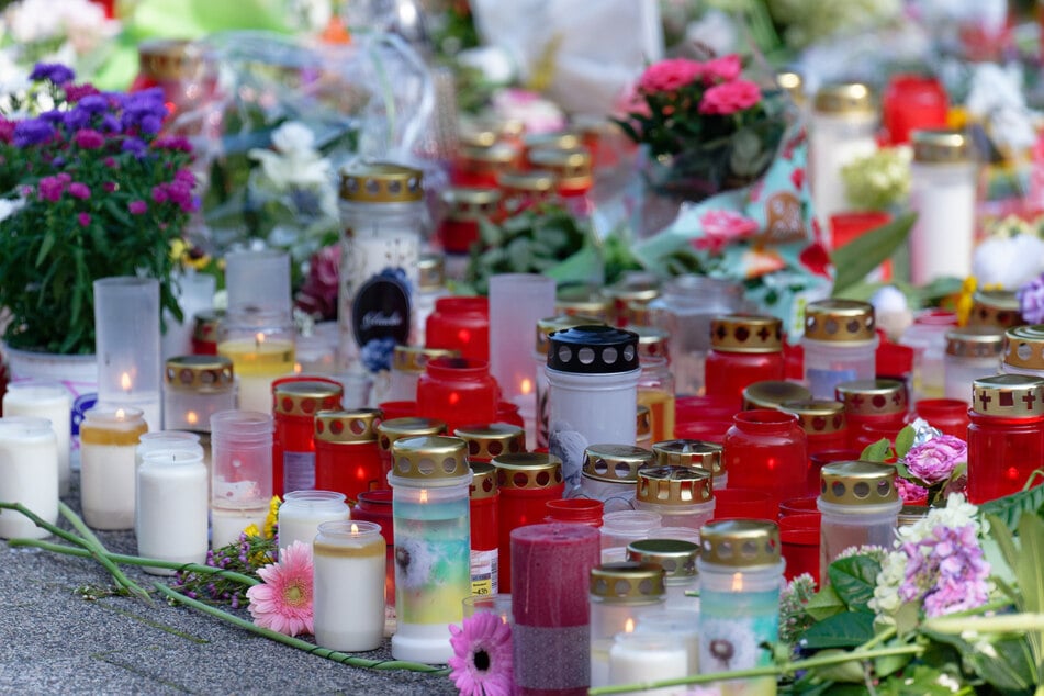 Blumen und Kerzen in Gedenken an die Opfer liegen an einer Kirche in der Nähe des Tatorts in der Solinger Innenstadt.