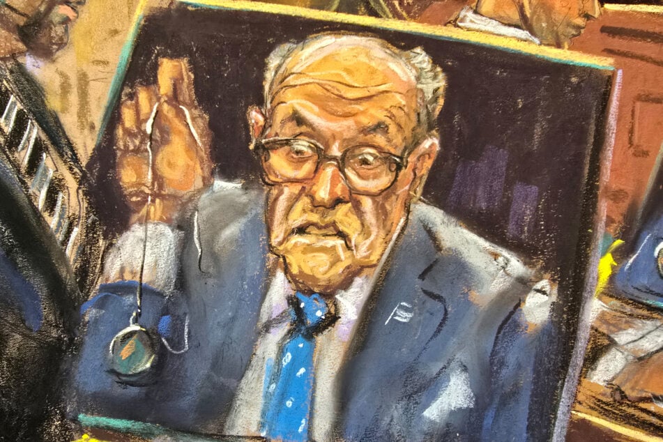 In a courtroom sketch, Rudy Giuliani holds up a watch he has not yet turned over while appearing remotely by video link during a hearing before a US district Judge.