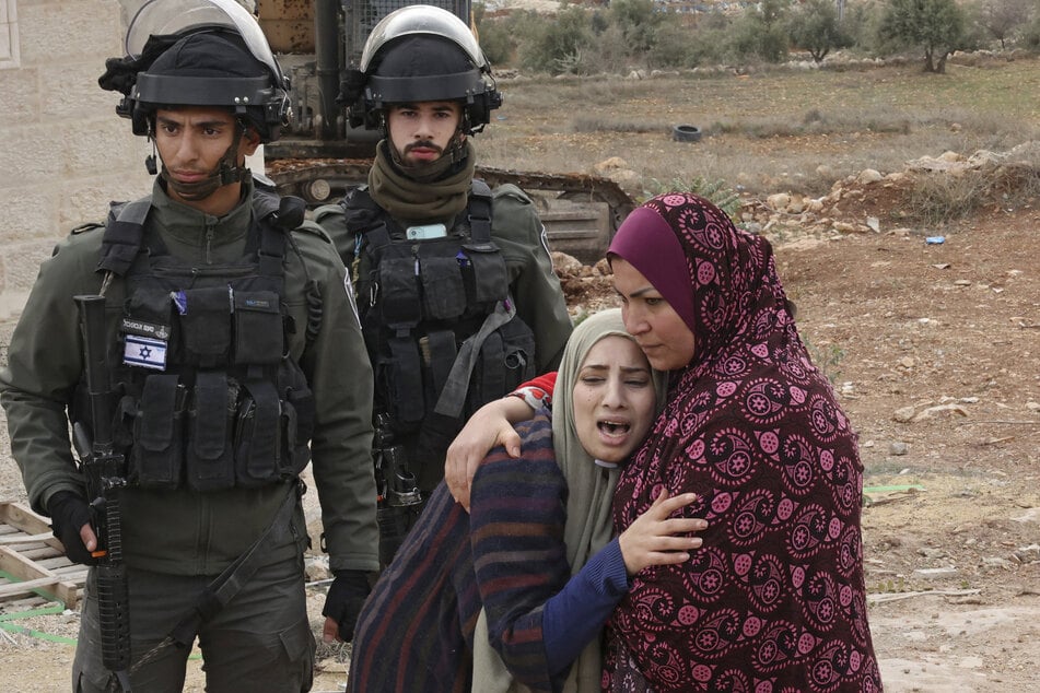 Israeli forces stand guard as Palestinian women react to the demolition of their home, located within "Area C" of the occupied West Bank.