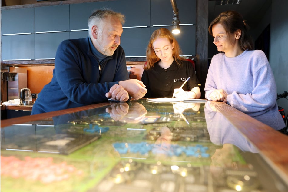 Pfiffige Tischplatte mit ausgemusterter Elektronik unter Glas: 4Source-Sprecher Werner Witt (56) im Gespräch mit Werksstudentin Sara Heimrich (24) und Einkaufsmanagerin Christin Muth (43, r.).