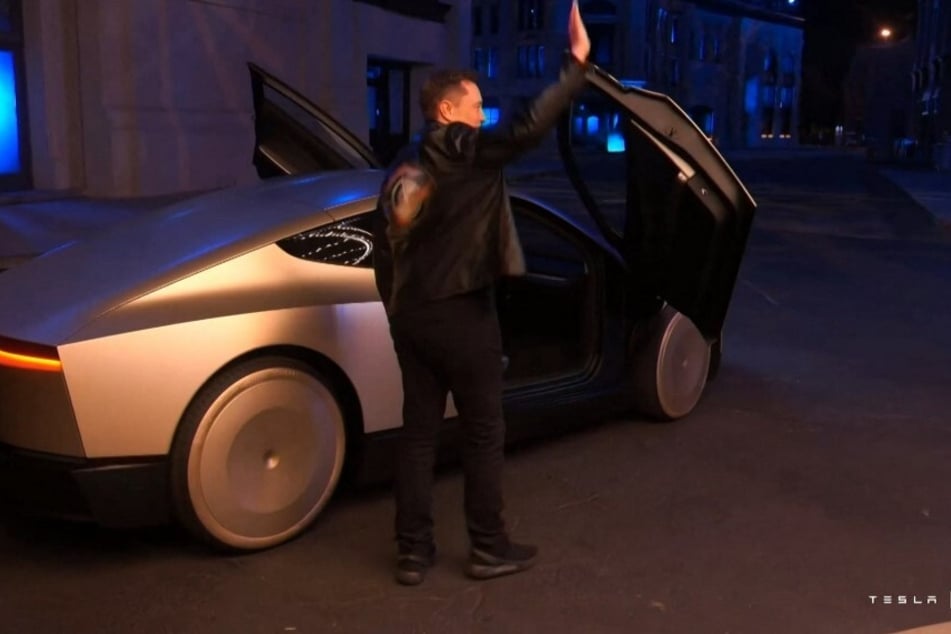 A video grab obtained October 10, 2024, shows Tesla CEO Elon Musk waving next to his long-promised robotaxi during a launch event at the Warner Brothers studio lot near Los Angeles.