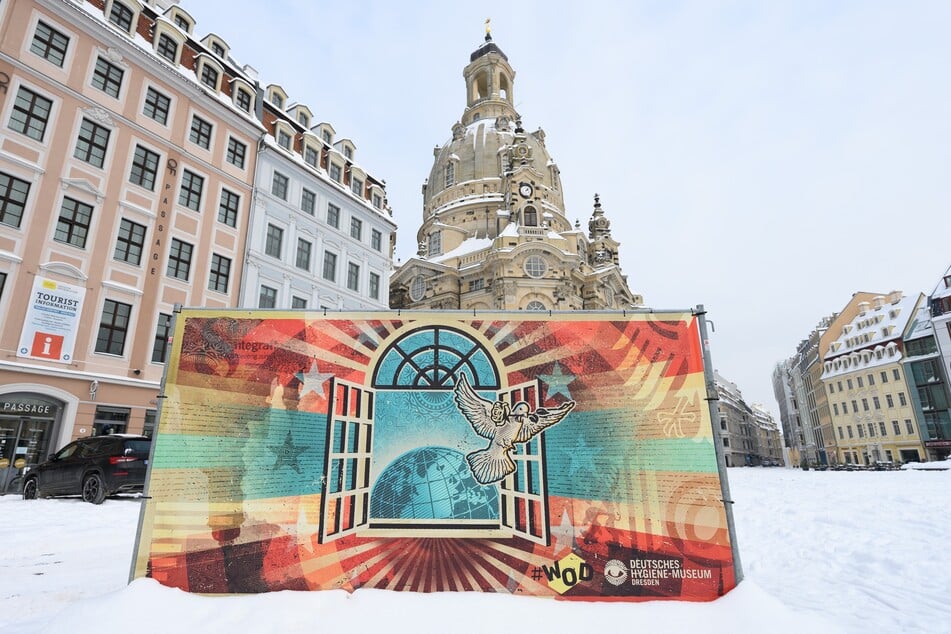 Ein Kunstprojekt der Initiative Weltoffenes Dresden #WOD mit einem Motiv des Streetartkünstler Lars P. Krause steht auf dem Neumarkt vor der Frauenkirche im Schnee.