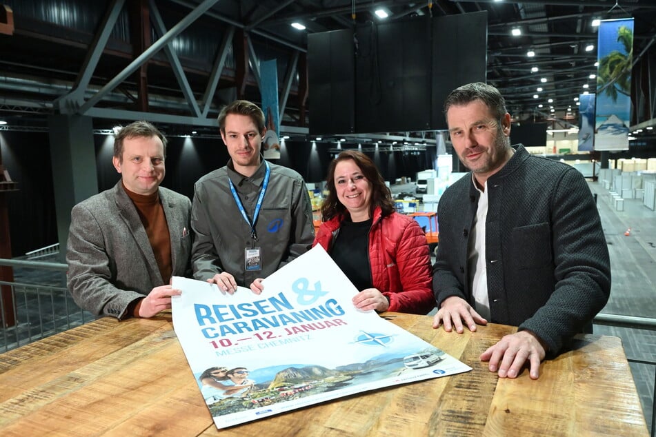 Die Organisatoren der Messe "Reisen &amp; Caravaning" zeigen das Plakat der Messe.