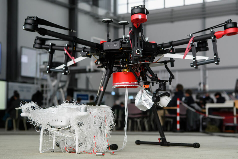 Eine von einer Jagddrohne des Typs "AirRobot AR200" (r.) gefangene Drohne steht im Fangnetz bei einer Präsentation. (Archivbild)