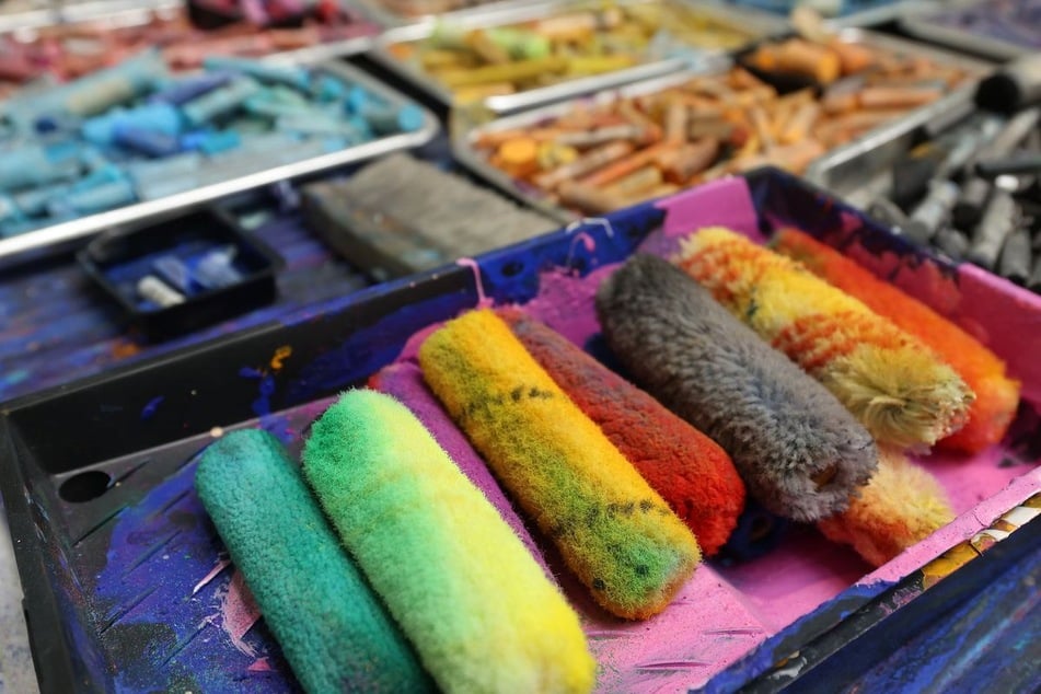 Bunte Lackwalzen und Kreide liegen auf einem Tisch in Macks Atelier in Mönchengladbach.