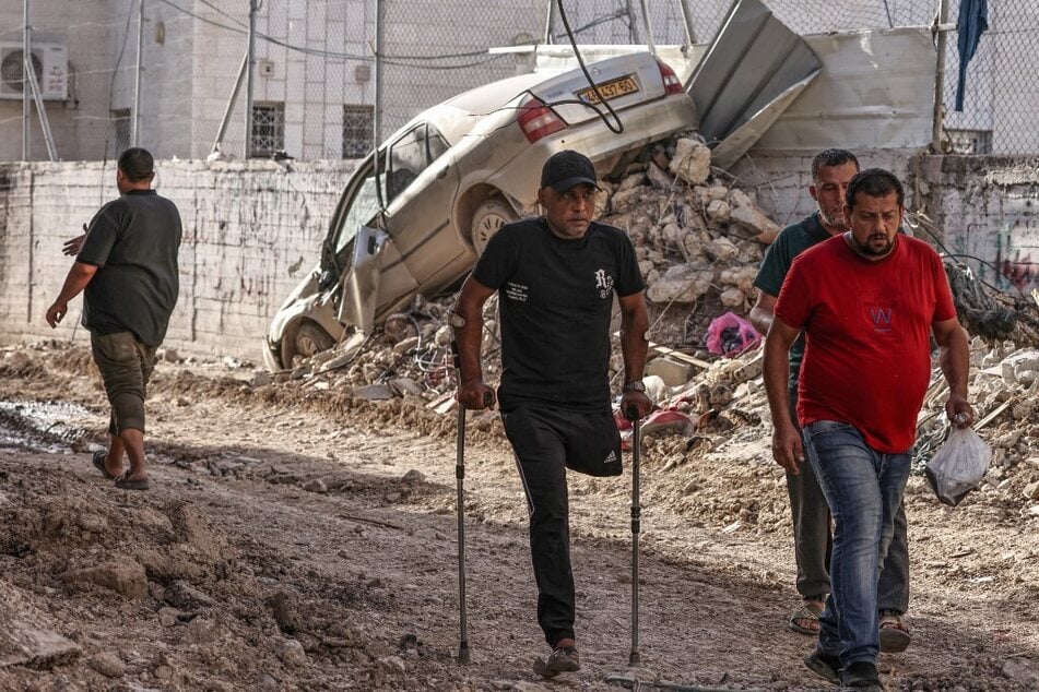 An amputee and other men walk amid the devastation following an Israeli army raid in Tulkarem in the north of the occupied-West Bank, on September 12, 2024.