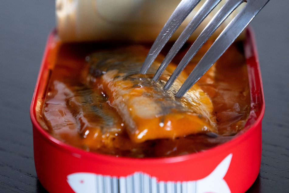 Eine Gabel steckt in einer Dose mit Heringsfilets.