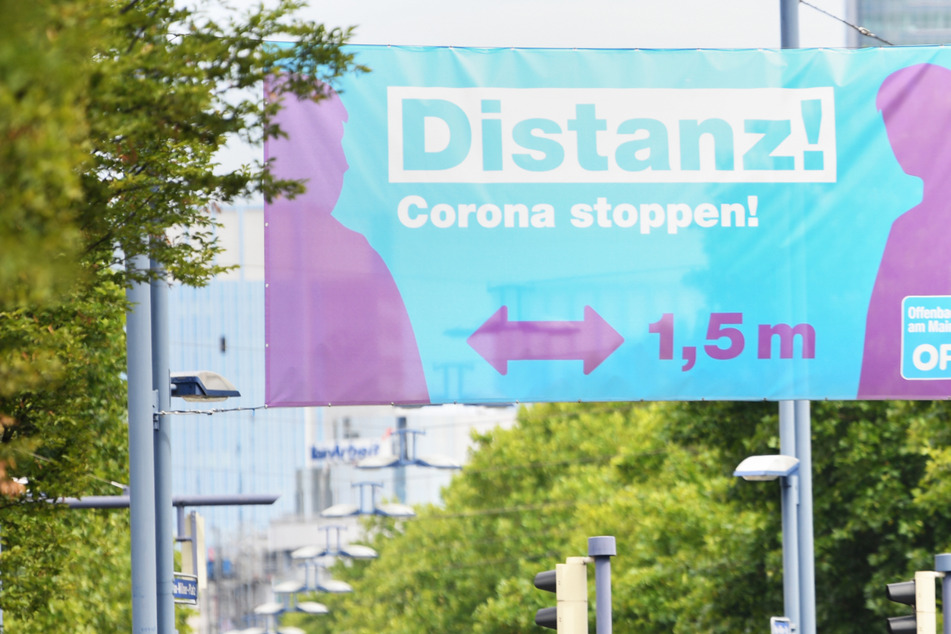 Ein Plakat mit der Aufschrift "Distanz! Corona stoppen!" prangt am Ortseingang – die Offenbacher Bürger müssen strengere Corona-Regeln beachten.