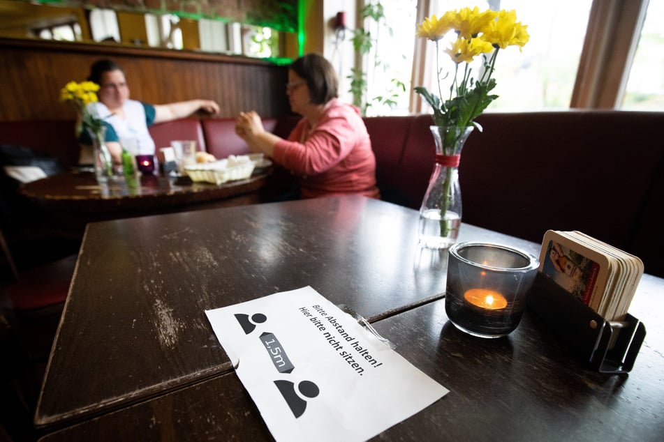 Ein Zettel mit der Aufschrift "Bitte Abstand halten!" liegt in einem Hamburger Lokal.