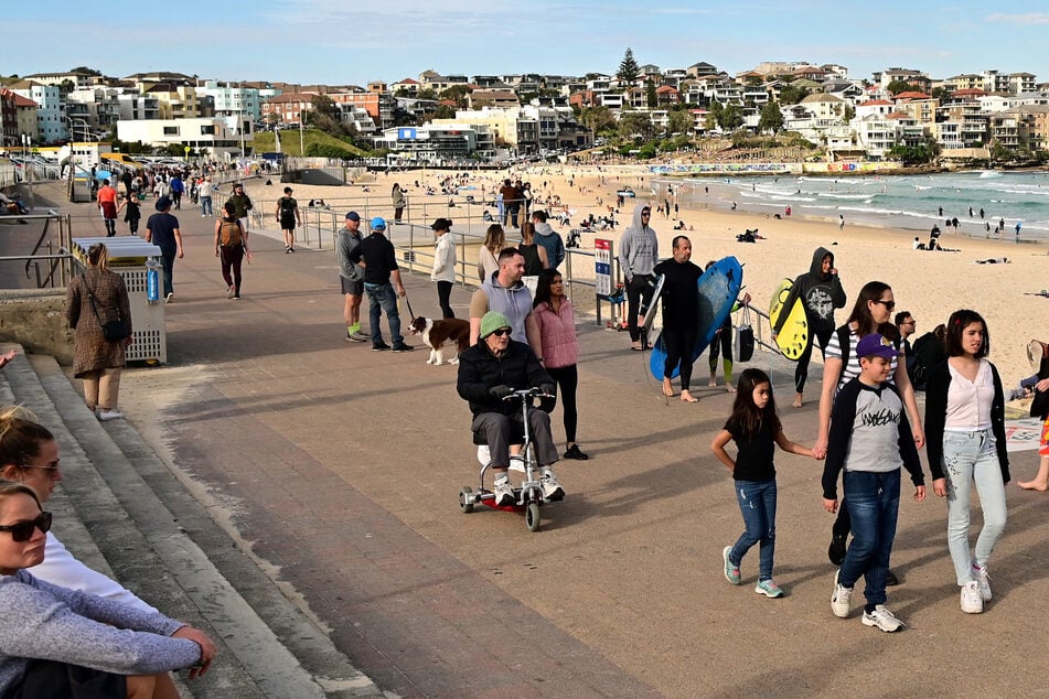 Menschen gehen an der Promenade des Bondi Beach spazieren.