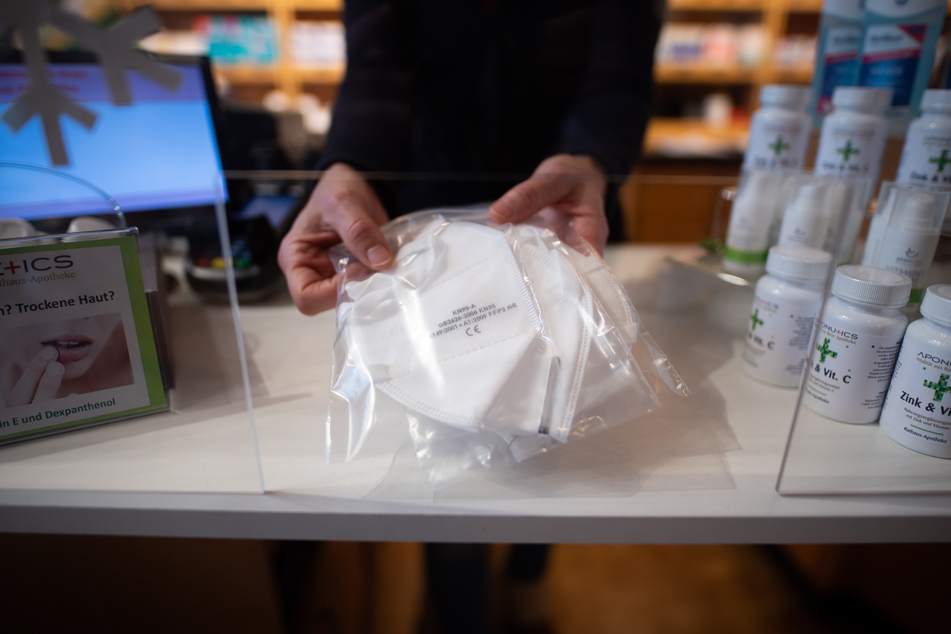 Eine Apothekerin reicht drei FFP2-Masken über einen Tresen.