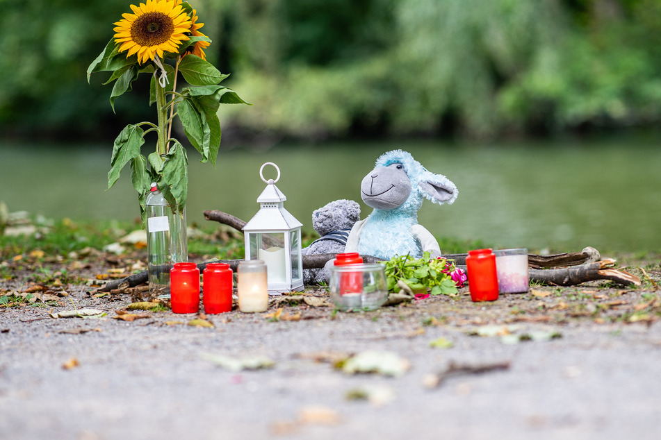 Zwei Stofftiere, Kerzen und Sonnenblumen stehen an dem kleinen See am Oberlandesgericht in Hamm, wo am Sonntag die Leiche der 25-Jährigen gefunden wurde.